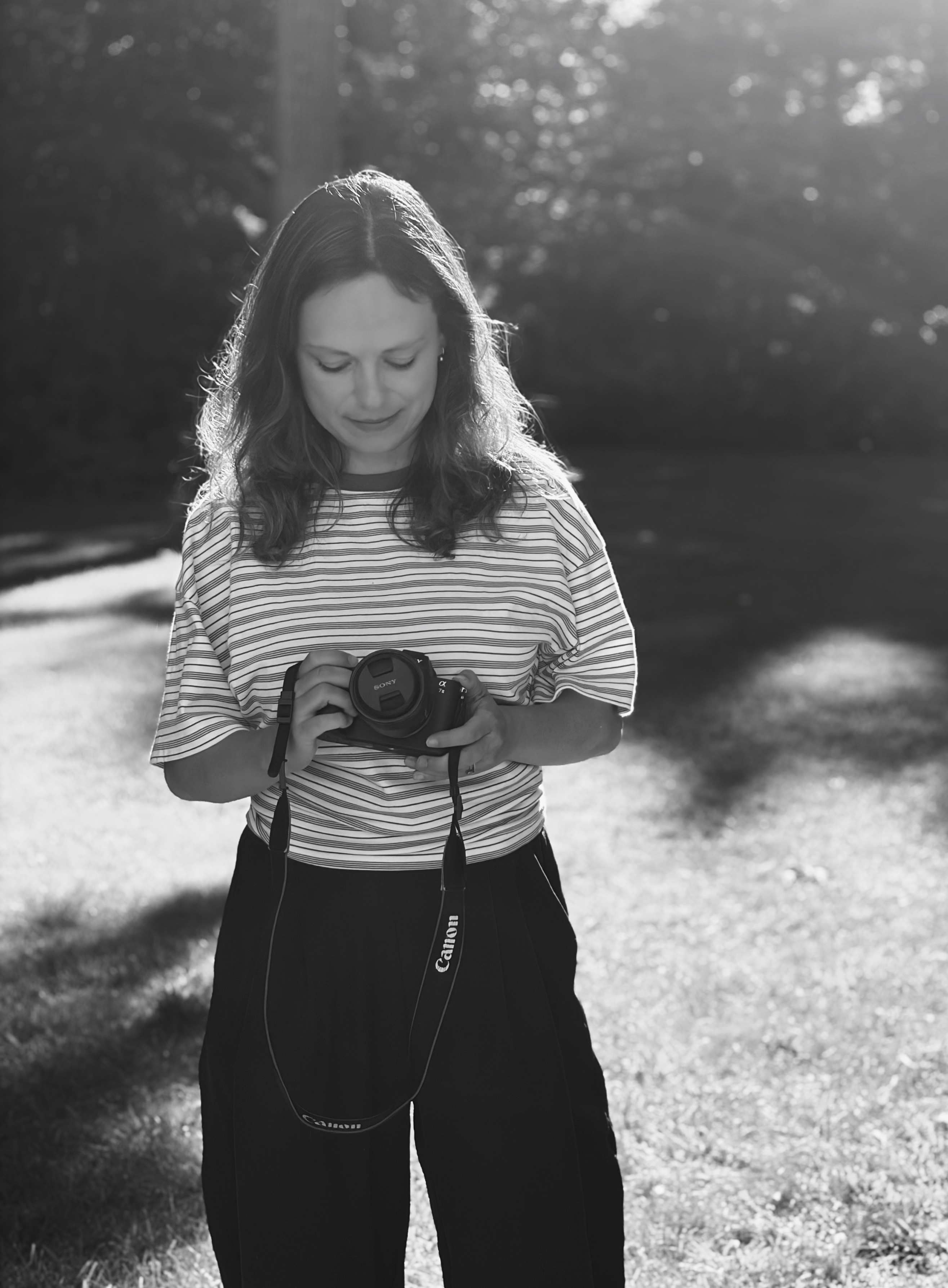 Black and white portrait of Anna looking down at her camera