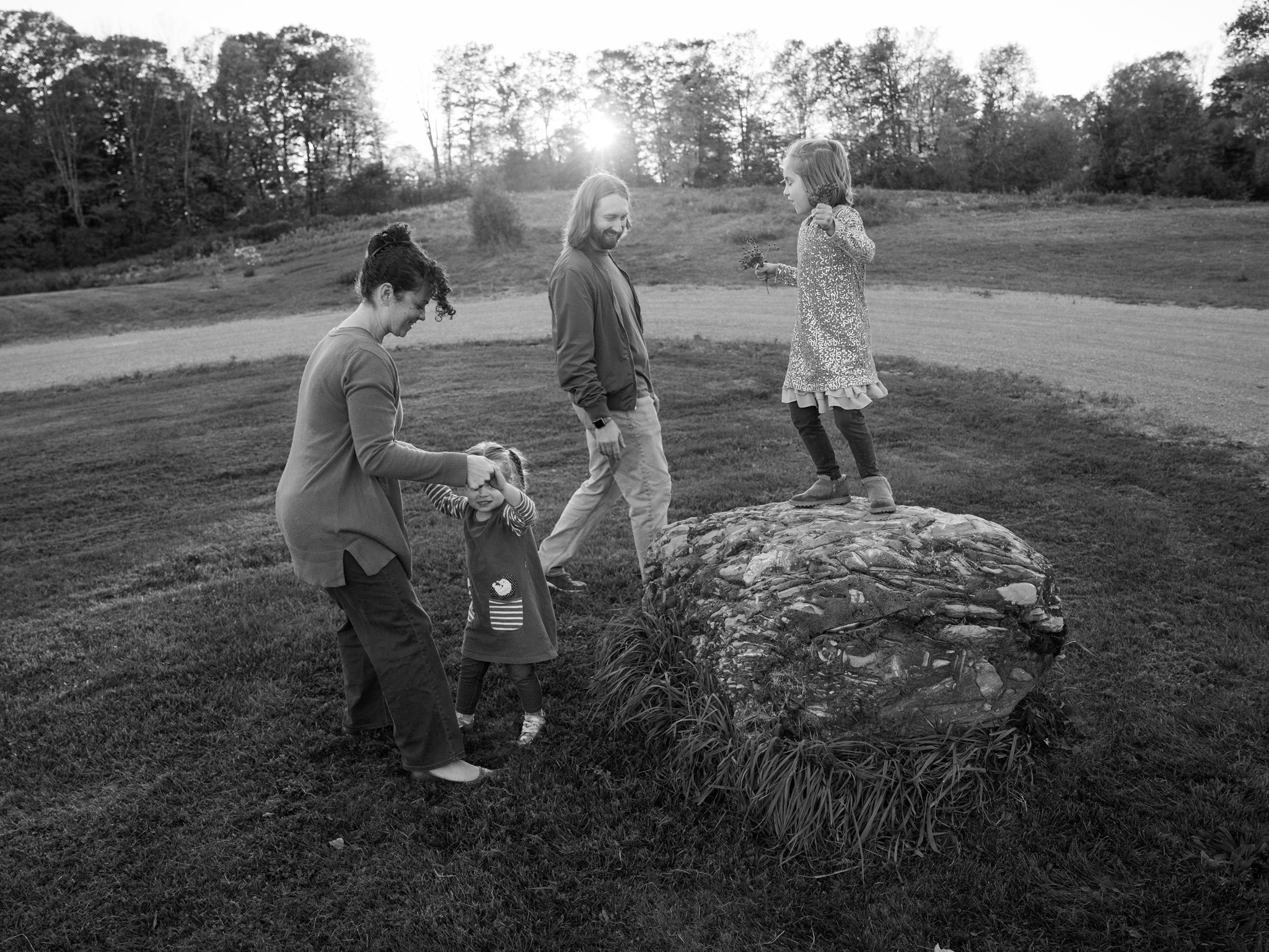 A family exploring together around a rock